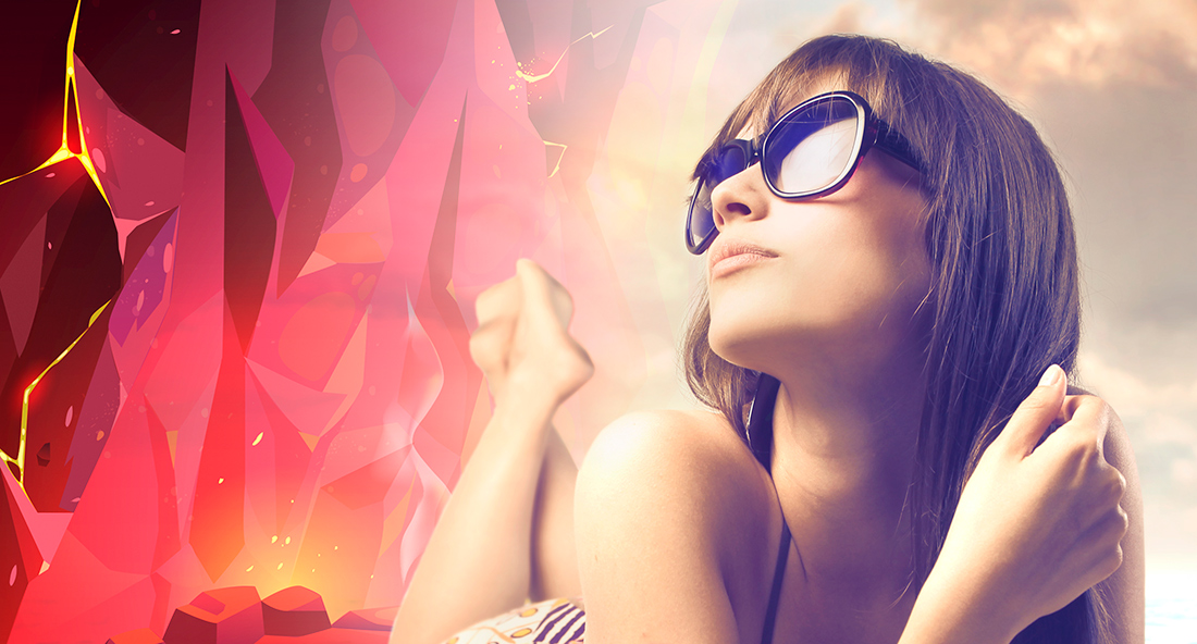 Young woman lounges lazily in the sun, her eyes gazing through retro-trendy sunglasses past the ominous volcanic heat nearby.